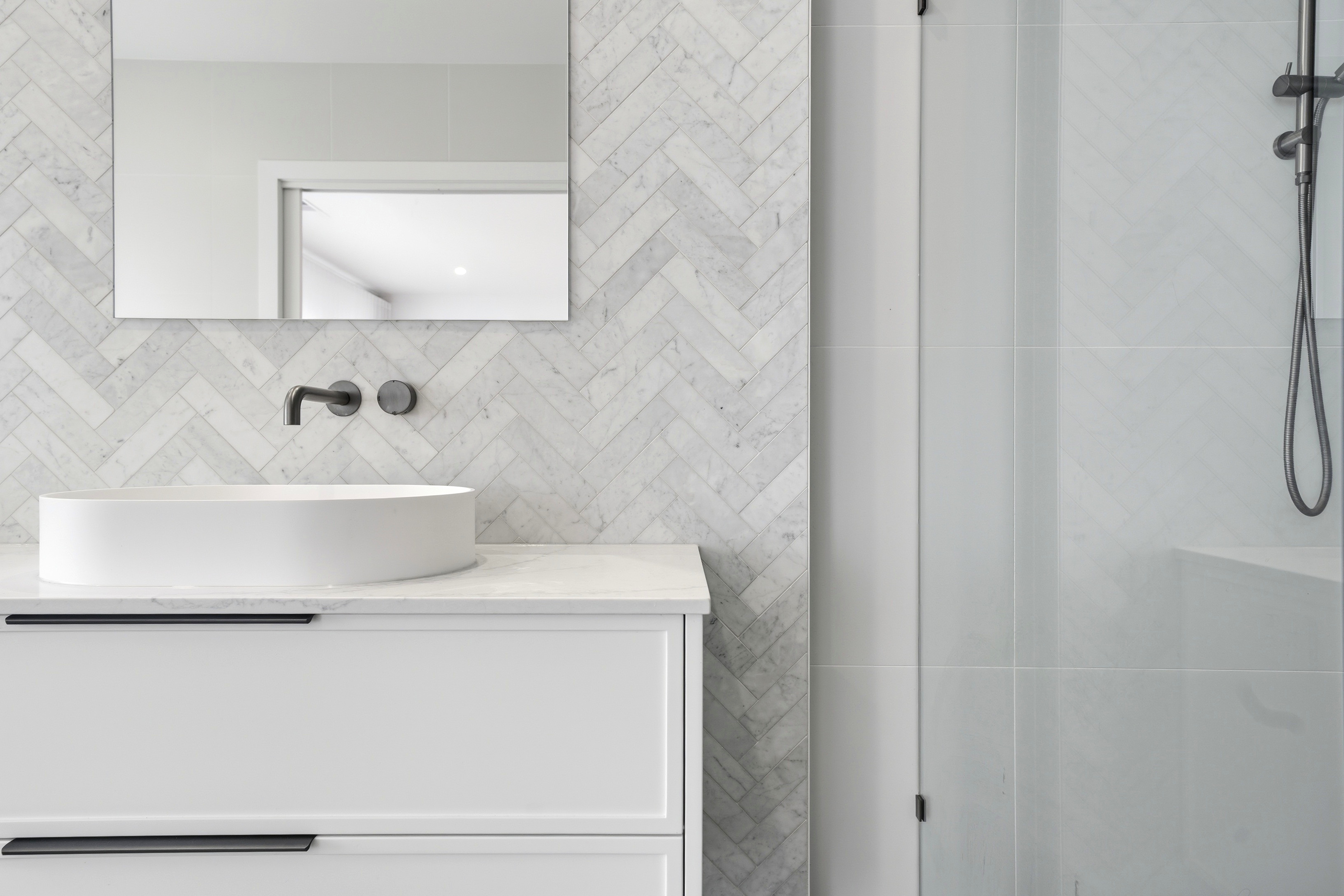 Ensuite vanity detail with herringbone marble tiles