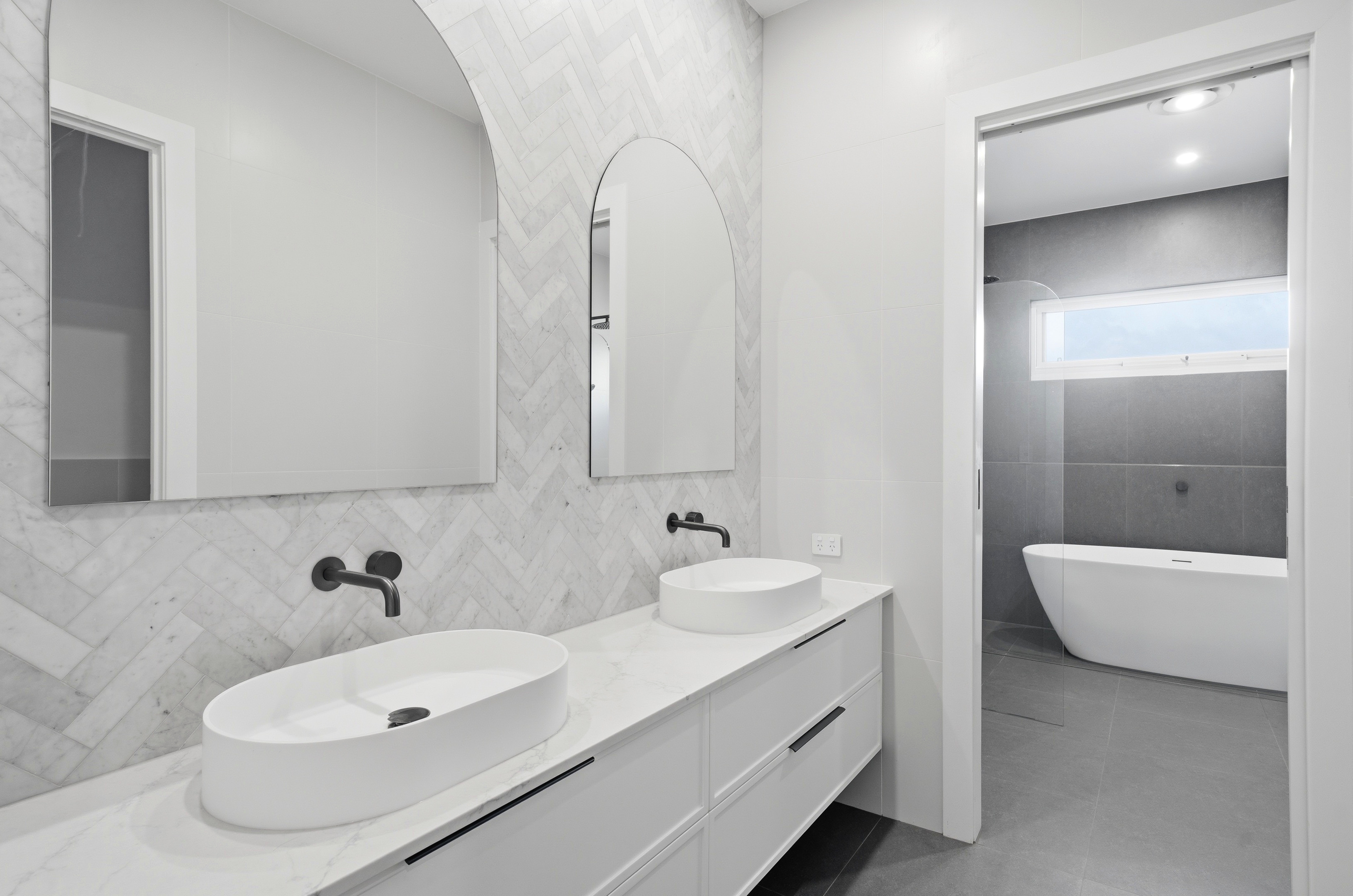 Ensuite dual vanities with herringbone marble feature wall