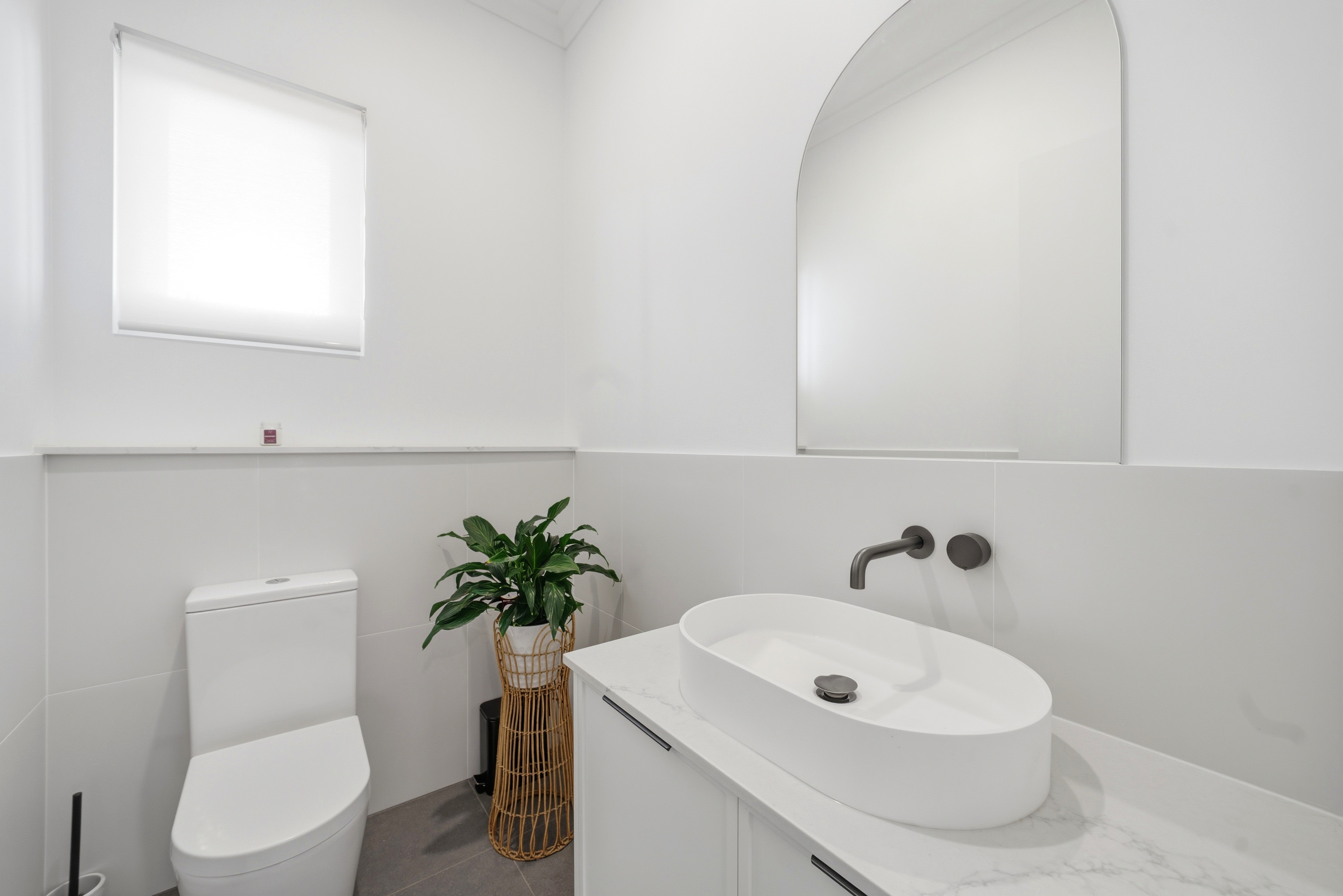 Powder room with arched mirror and stone-top vanity